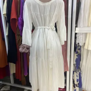 White, long-sleeved, tiered maxi dress featuring a fitted waist and flared cuffs. Free Size
