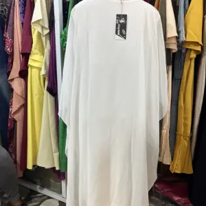 White kaftan-style maxi dress,a loose, flowing silhouette with wide, draped sleeves and a simple round or scoop neckline.