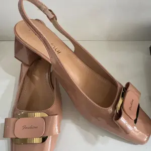 Nude patent leather slingback pumps, in a square toe and block heel, similar to Aaron Fairy