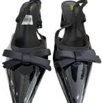 Black patent slingback block pump heels in a pointed toe and bow accent.